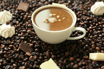 Cup of coffee with sweets and coffee beans closeup
