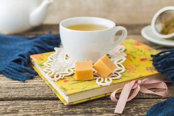 White cup of chamomile tea and book on table.