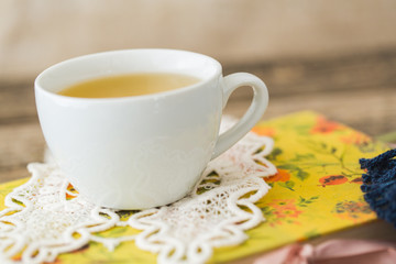 White cup of chamomile tea and book on table.
