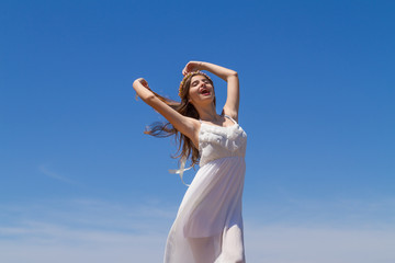 Fototapeta na wymiar Young brunette in white flimsy dress enjoys the summer sun.