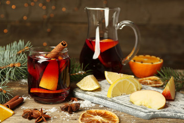 Mulled wine in glass bank with fruits and jug on decorated wooden table