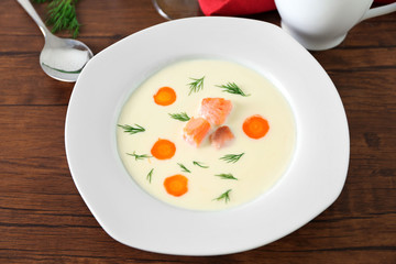 Delicious cream soup with salmon and carrot in white bowl