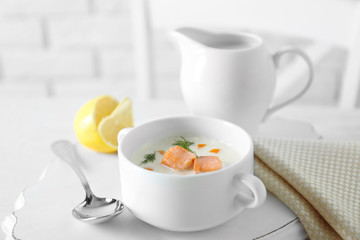 Delicious salmon cream soup on white decorated with lemon and cotton serviette table in the restaurant