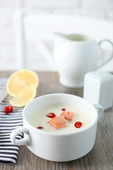 Tasty fish cream soup, lemon, salt and striped cotton serviette on wooden table, close up