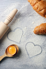 Hearts of flour and rolling pin on light background