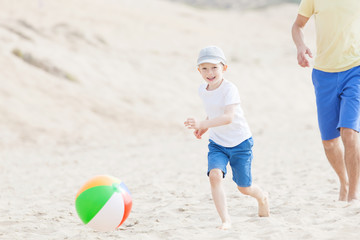 family playing with ball at the beach