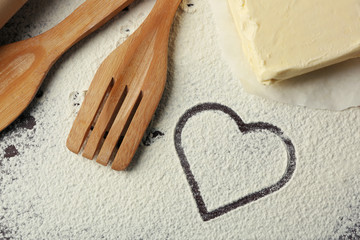 Fototapeta na wymiar Heart of flour and kitchen utensils on wooden background
