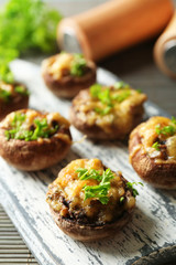 Stuffed mushrooms on wooden board, on table background