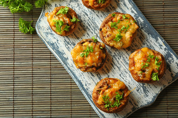 Stuffed mushrooms on wooden board, on table background