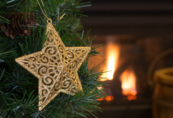 Gold Christmas Star Hanging on a Tree With Fireplace in Background