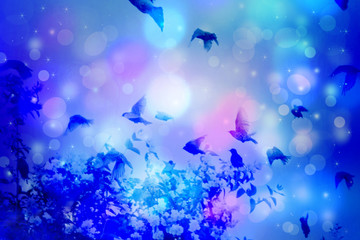 Fototapeta na wymiar Dreamy winter scene with starling birds flying against blue sky with bokeh light