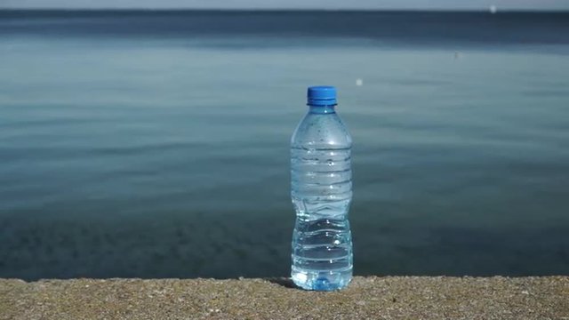 Water plastic bottle outdoor on sea shore 4K