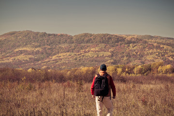 Male tourist with backpack sotret on the horizon in autumn