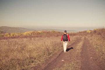 Male tourist with backpack is on a rural road