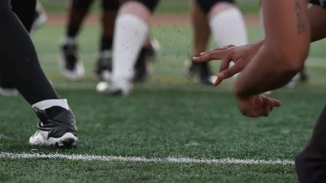 Close up of a football player kicking the ball toward the goal posts