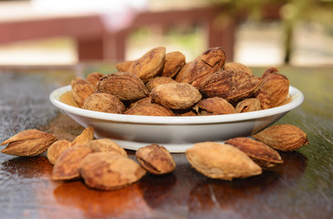 Seeds, almonds, toasted on wood  table  Keep the focus on plate  almonds seeds Blur the foreground and background .
