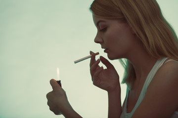Obraz premium Girl using lighter to light cigarette.