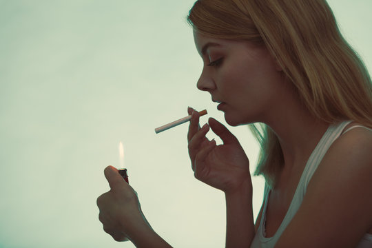 Girl using lighter to light cigarette.