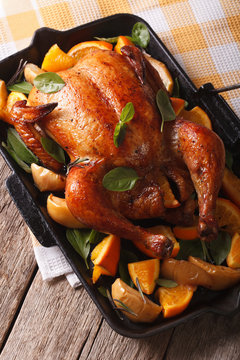 roast chicken with oranges and apples close-up in a pan. vertical
