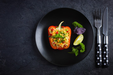pepper staffed with coucous and vegetables on black plate