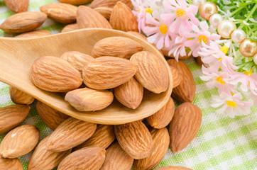 Almonds in wooden spoon with flower.