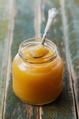 Lemon curd in glass jar on rustic wooden table, traditional fruit cream, vintage style