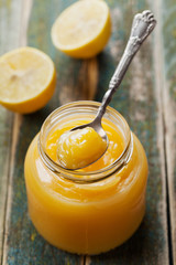 Lemon curd in glass jar on rustic wooden table, traditional fruit cream, vintage style
