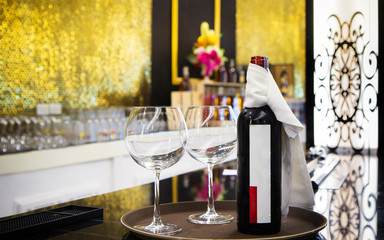 Bottle and two glasses of red wine together on a tray served