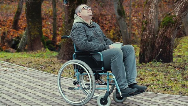 Disabled man in wheelchair breathe fresh air at outdoors
