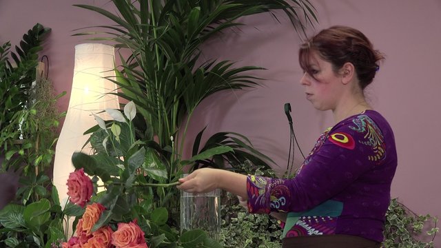 a florist manufactures a bouquet of roses