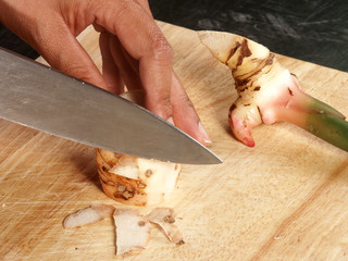 Galangal cut by knife on chopping board  
