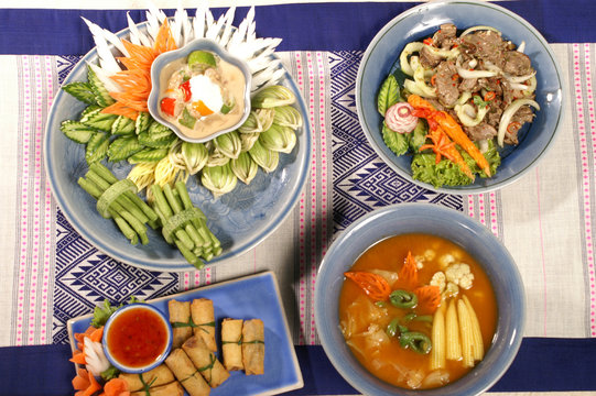 healthy thai food set with snack luxery serve. chili paste and mixed vegetable, meat salad spicy herb,  red curry soup mixed vegetable and fried spring roll. 