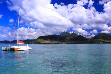 Lonely catamaran floating near the Mauritius island seen in the background