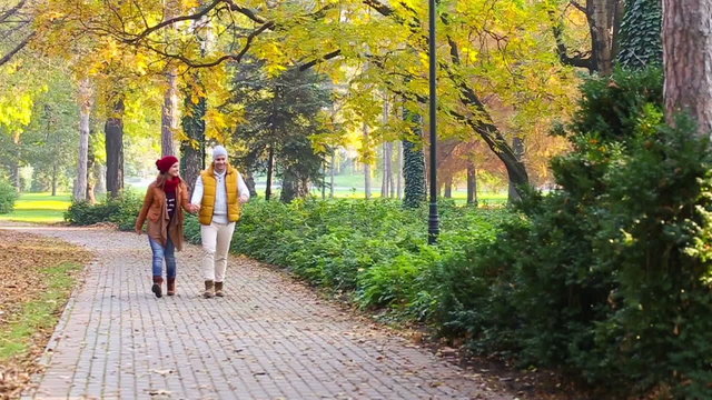 Romantic young couple walking in the park, walking, kissing and holding hands. Slow motion.