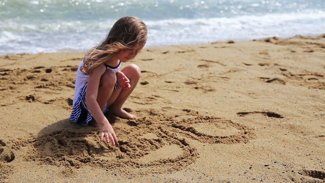Girl drawing and jumps on  a sand beach.