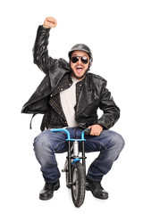 Fototapeta na wymiar Excited motorcyclist riding a tiny bicycle