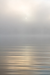 Morning sun through fog at lake