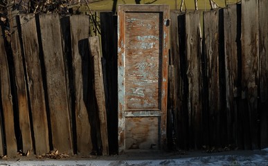 abandoned wooden door with peeling blue paint and curve wooden fence