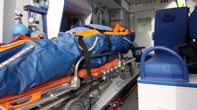 Emergency medical service paramedics load heavy senior patient on stretcher into ambulance