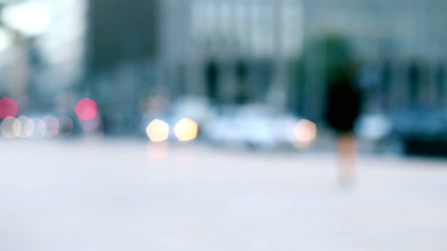 anonymous man walking alone in the street in a blurred out of focus colorful background of urban context