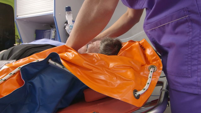 EMT provide emergency medical care for critical senior patient in ambulance and transport to the nearest hospital