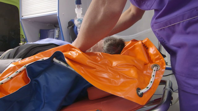 EMT paramedic provide emergency medical care for critical senior patient in ambulance using an oxygen mask and transport to the nearest hospital