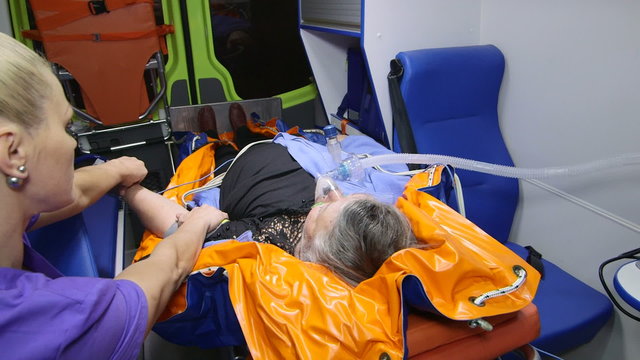 Paramedic provide medical care to obese senior patient in emergency ambulance measuring blood pressure