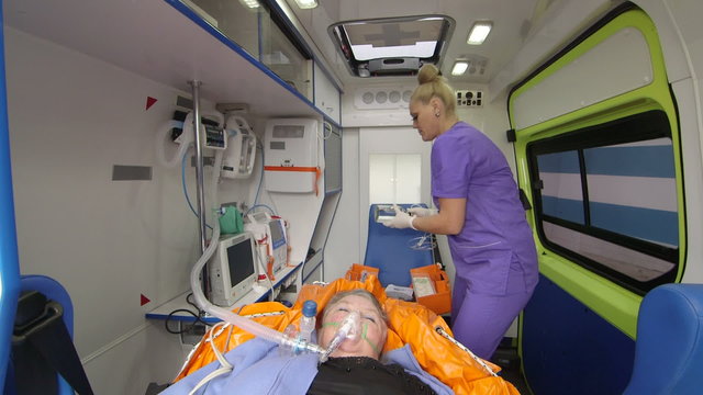 Paramedic provide emergency medical care to critical patient in ambulance preparing an iv drip intravenous infusion