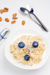 Oatmeal porridge with berries and nuts in bowl, top view