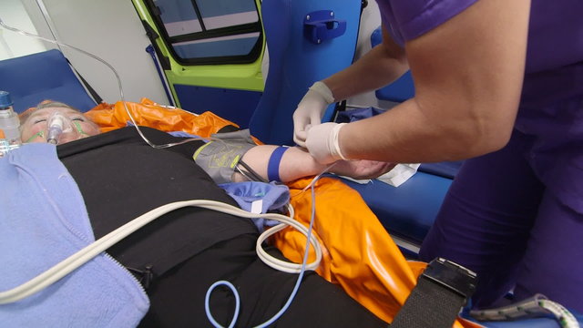 Senior person receiving medication via intravenous therapy in ambulance during transportation to hospital