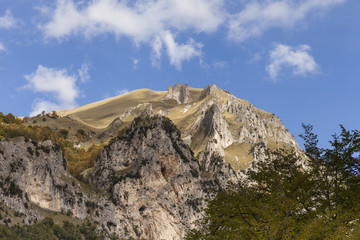 Cima di una montagna all'orizzonte.  Cielo blu con nuvole bianche