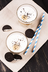 Coffee latte with chocolate cookies over black wooden background. Tasty breakfast concept. Selective focus