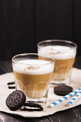Coffee latte with chocolate cookies over black wooden background. Tasty breakfast concept. Selective focus