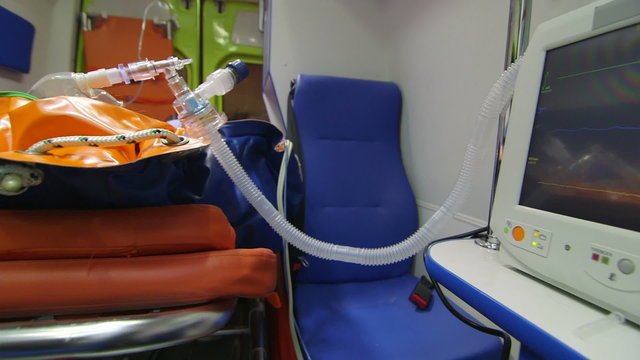 EMT paramedic provide emergency medical care to person in ambulance monitoring high blood pressure on screen of multiparameter patient monitor pan shot closeup